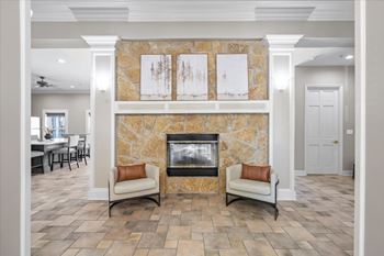 A living room with a stone fireplace and two chairs.